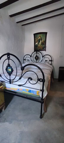 Charming bedroom with wrought iron bed and traditional decor in Somontin, Almeria.