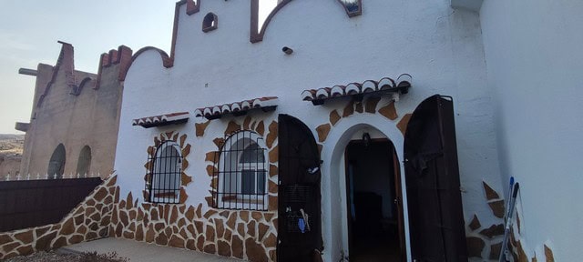 Cave house with traditional stone facade and arched windows in Villanueva de las To, Granada.