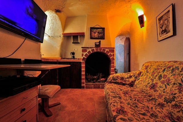 Charming cave house living room with fireplace and rustic decor in Villanueva de las To, Granada.