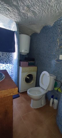 Cozy cave house bathroom with blue mosaic tiles and modern fixtures in Villanueva de las To, Granada.