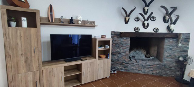 Cozy living room with modern furniture and a stone fireplace in Villanueva de las To, Granada.