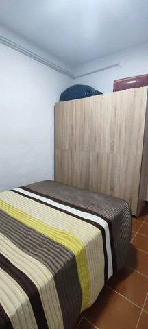 Cozy bedroom with wooden wardrobe and simple decor in a rural Granada home.
