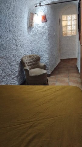 Interior view of a cave house in Cantarranas, Granada, featuring rustic white walls and cozy furnish.