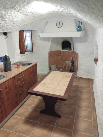 Cave house interior with rustic kitchen, cozy fireplace, and traditional decor in Cantarranas, Grana.