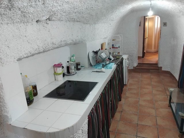 Cave house kitchen with white tiled counter, cooking appliances, and rustic interior in Cantarranas,.