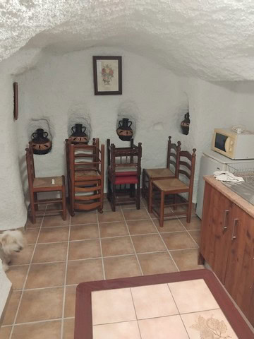 Cozy interior of a cave house with traditional wooden chairs and rustic decor in Cantarranas, Granad.