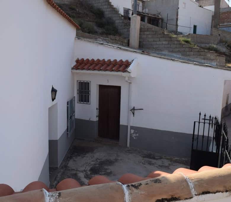 Cave house exterior in Caniles, Granada, with traditional white walls and terracotta roof tiles.