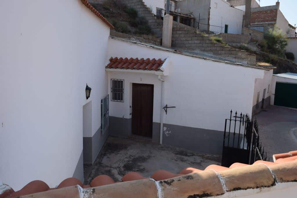 Cave house exterior in Caniles, Granada, with traditional white walls and terracotta roof tiles.