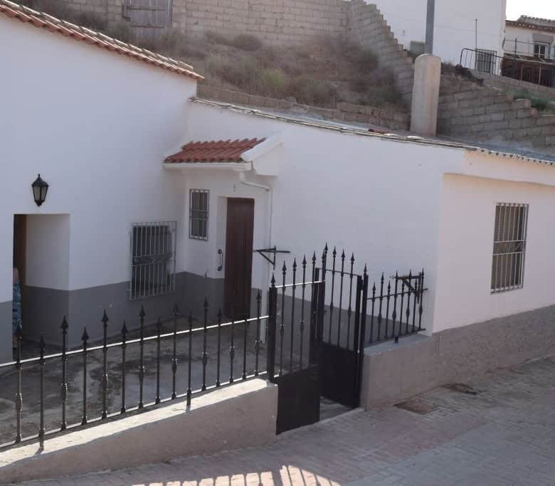 Traditional cave house in Caniles, Granada, with whitewashed walls and a gated entrance.