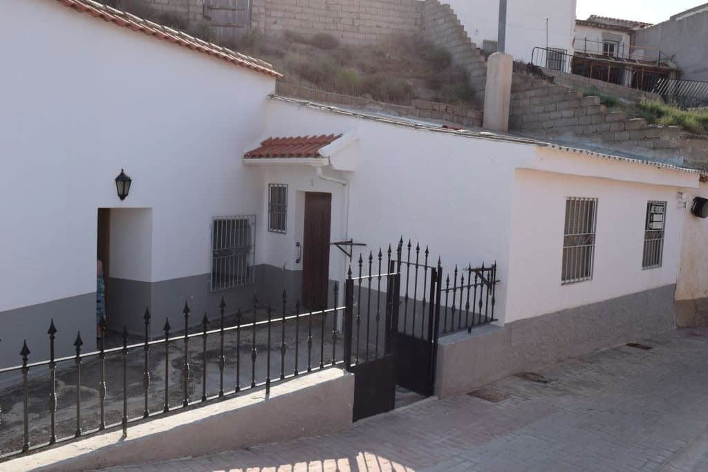 Traditional cave house in Caniles, Granada, with whitewashed walls and a gated entrance.
