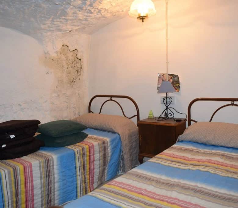 Unique cave house interior in Caniles, Granada, featuring rustic walls and cozy bedrooms.