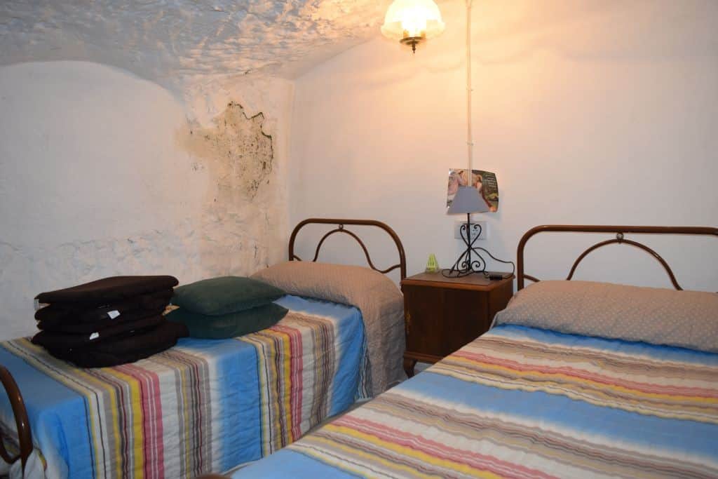 Unique cave house interior in Caniles, Granada, featuring rustic walls and cozy bedrooms.