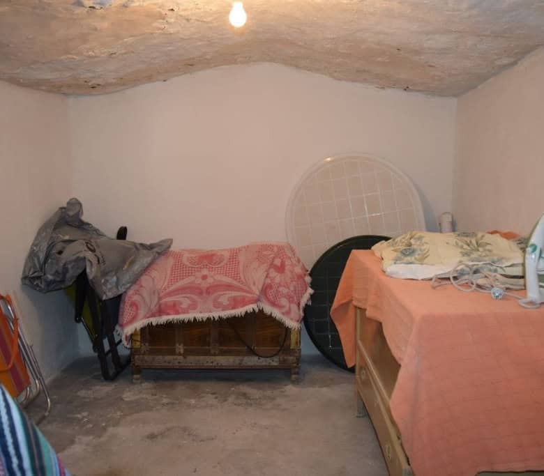 Cave house interior in Caniles, Granada, with simple furnishings and low ceiling.