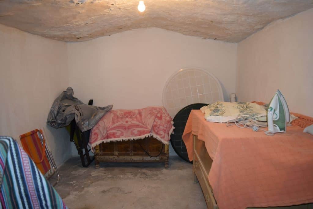 Cave house interior in Caniles, Granada, with simple furnishings and low ceiling.