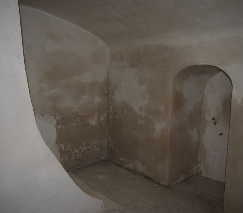 Cave house interior with arched doorway in Caniles, Granada, showcasing rustic stone walls and uniqu.