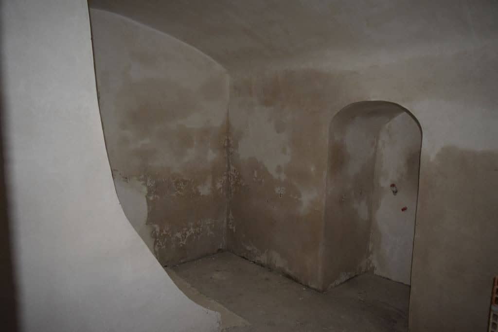 Cave house interior with arched doorway in Caniles, Granada, showcasing rustic stone walls and uniqu.