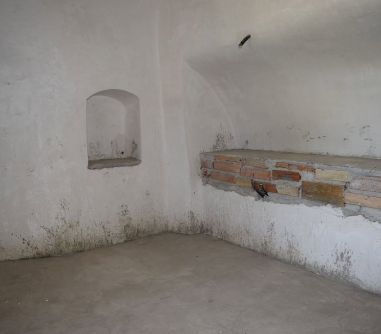 Interior of a rustic cave house in Caniles, Granada with white walls and brick accents.