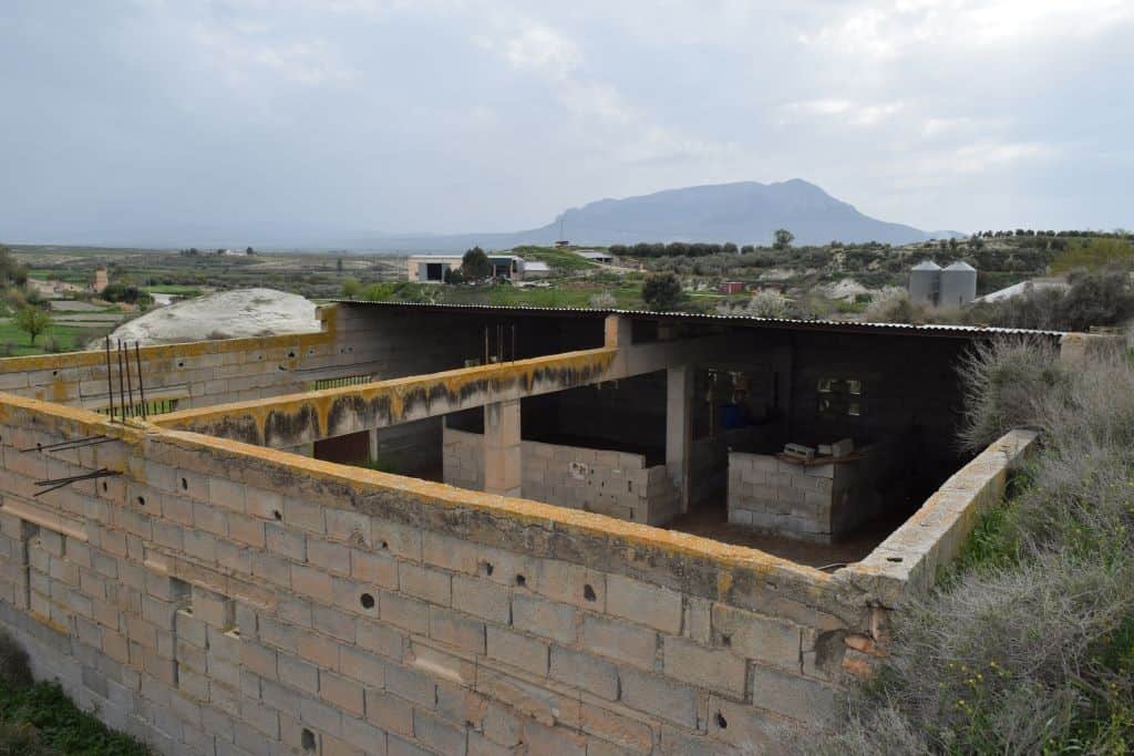 Cave house under construction in Benamaurel, Granada, with scenic mountain views in the background.