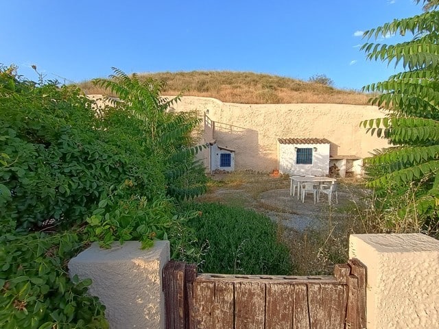 Cave house with outdoor seating in Cortes de Baza, Granada, surrounded by lush greenery and natural.
