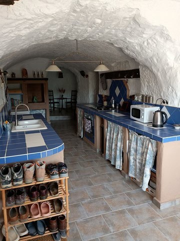 Cave house kitchen with blue tiles, rustic furniture, and stone walls in Cortes de Baza, Granada.