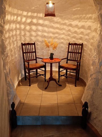 Charming cave house interior with two wooden chairs and a small table in Cortes de Baza, Granada. Un.