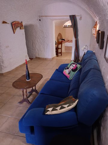 Charming cave house living room with white textured walls and cozy blue sofa in Cortes de Baza, Gran.