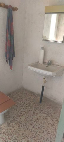 Village property with a small sink and mirror in a rustic setting, ideal for a cozy rural home.