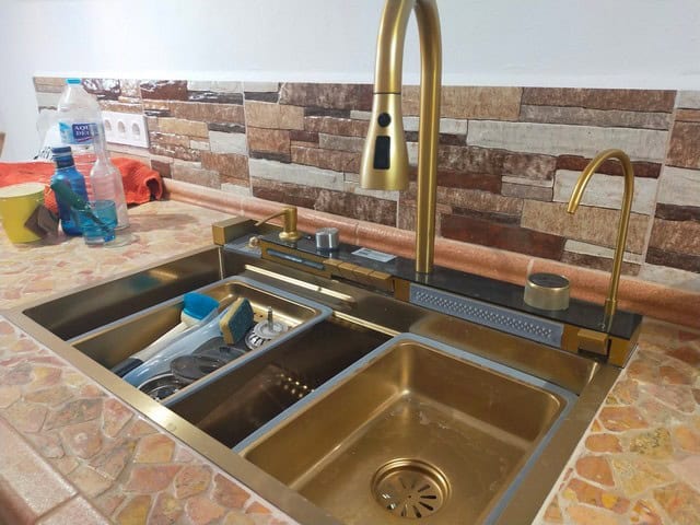 Spacious kitchen with modern gold-colored sink and fixtures in a village home in Urracal, Almeria.