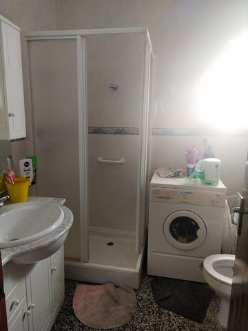 Compact bathroom with shower, washing machine, and sink in Velez Blanco, Almeria.