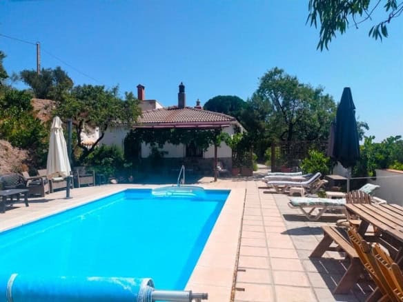 Swimming pool at rural property in Seron, Almeria with outdoor seating and lush greenery.