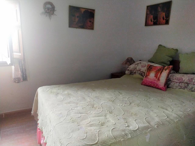 Comfortable bedroom with bed, pillows, and wall art in a rural Almeria home.