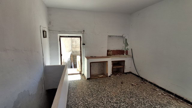 Interior view of a town house in Tijola, Almeria, showing unfinished walls and fireplace.