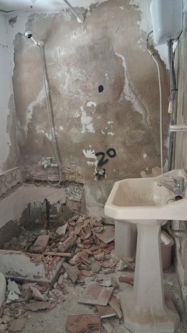 Interior of a renovation project in Tijola, Almeria, showing damaged walls, exposed plumbing, and co.