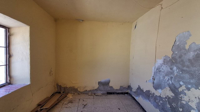 Interior of a rustic town house in Tijola, Almeria, showing worn walls and a window.