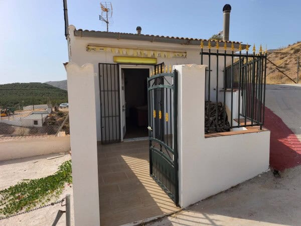 Charming cave house with entrance gate in Huesa, Jaen, surrounded by scenic hills and rural landscap.