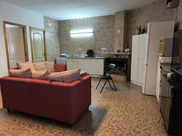 Spacious cave house living area with kitchen, sofa, and basic amenities in Huesa, Jaen. Unique under.