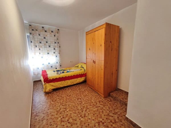 Charming cave house interior in Huesa, Jaen, featuring a cozy bedroom with a single bed and wooden w.