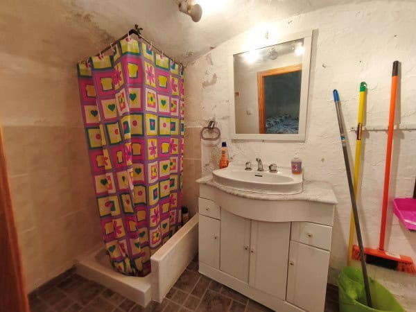 Charming cave house bathroom with shower, mirror, and rustic decor in Huesa, Jaen.