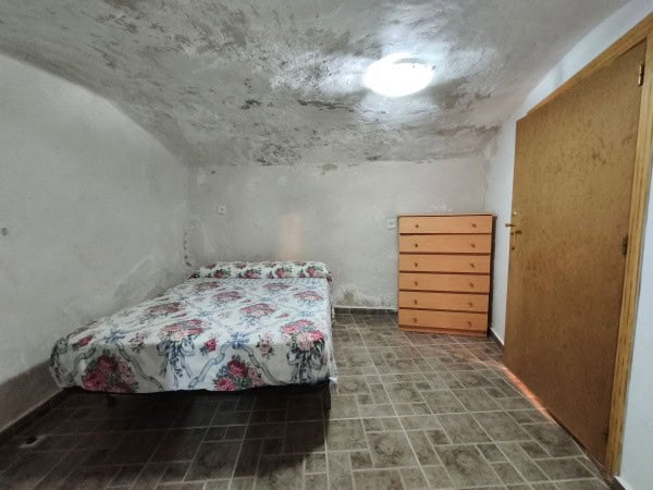 Cave house interior in Huesa, Jaen with simple furnishings and rustic charm.