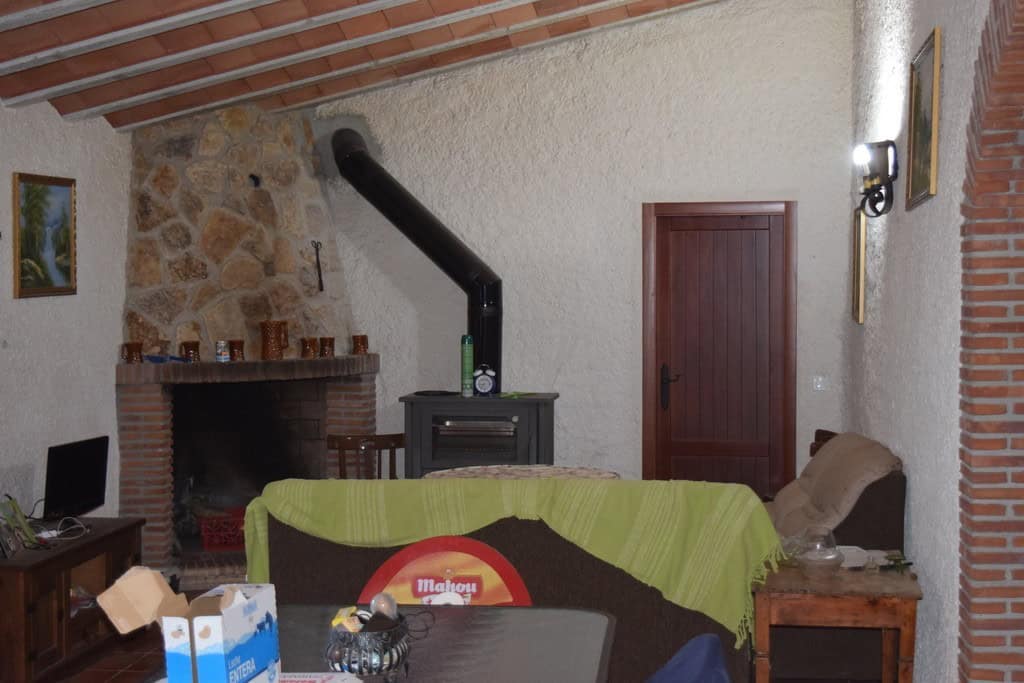 Charming interior of a cave house in Cuevas del Campo, Granada, featuring a fireplace, wooden door,.