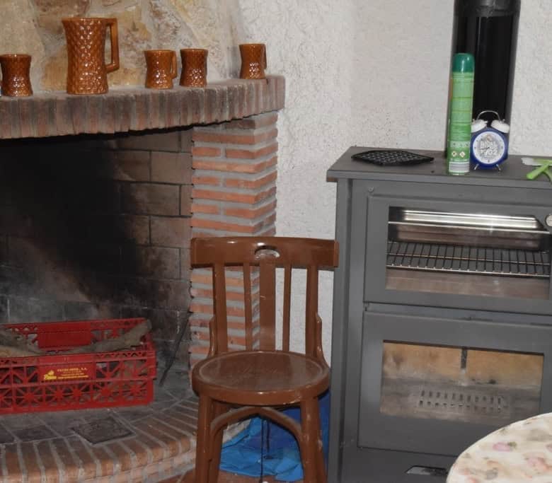 Cave house interior with fireplace, wooden chair, and stove in Cuevas del Campo, Granada.