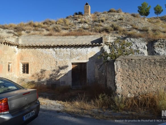 Cave house in Cullar, Granada, with rustic stone walls and a scenic hillside backdrop.