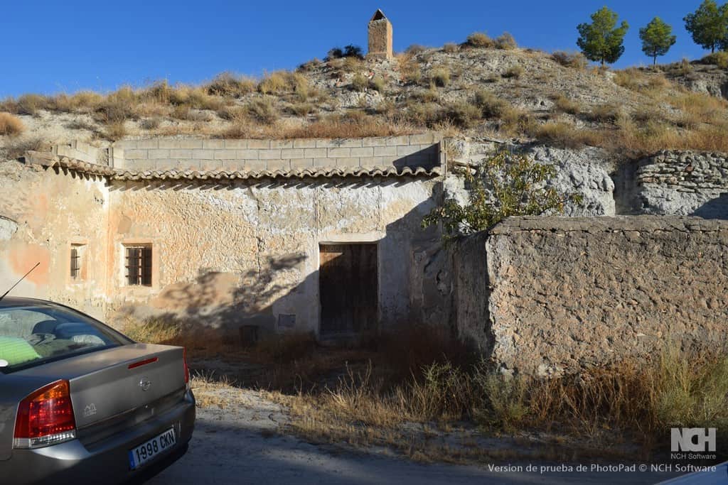 Cave house in Cullar, Granada, with rustic stone walls and a scenic hillside backdrop.