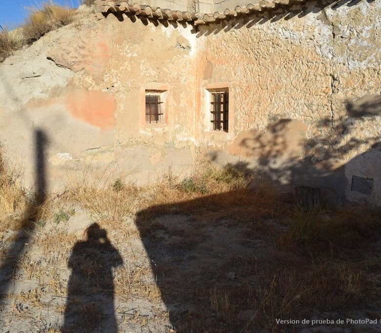 Cave house in Cullar, Granada, with rustic stone walls and small windows, set in a dry, sunny landsc.