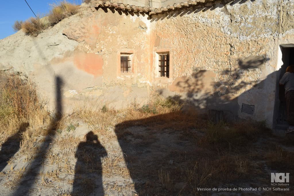 Cave house in Cullar, Granada, with rustic stone walls and small windows, set in a dry, sunny landsc.