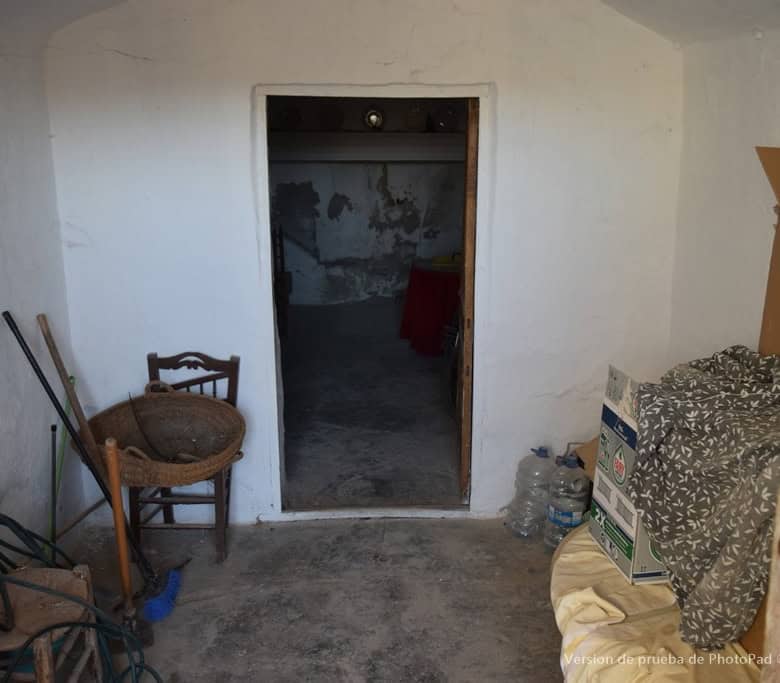 Charming cave house interior in Cullar, Granada, featuring rustic walls and simple furnishings.