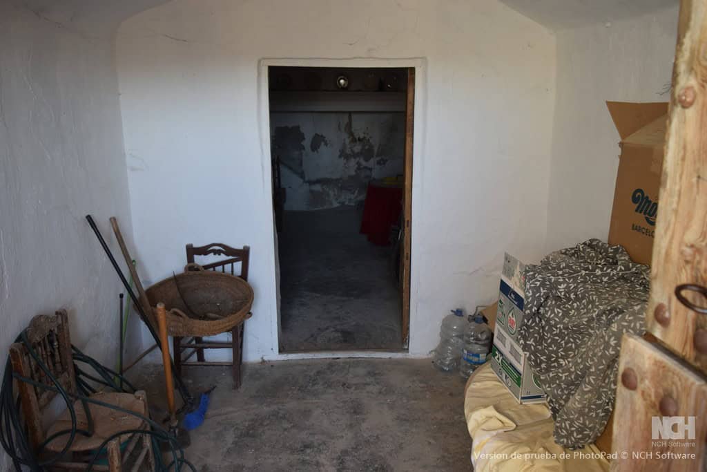Charming cave house interior in Cullar, Granada, featuring rustic walls and simple furnishings.