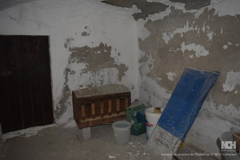Interior of a rustic cave house in Cullar, Granada, showing aged walls and basic furnishings.