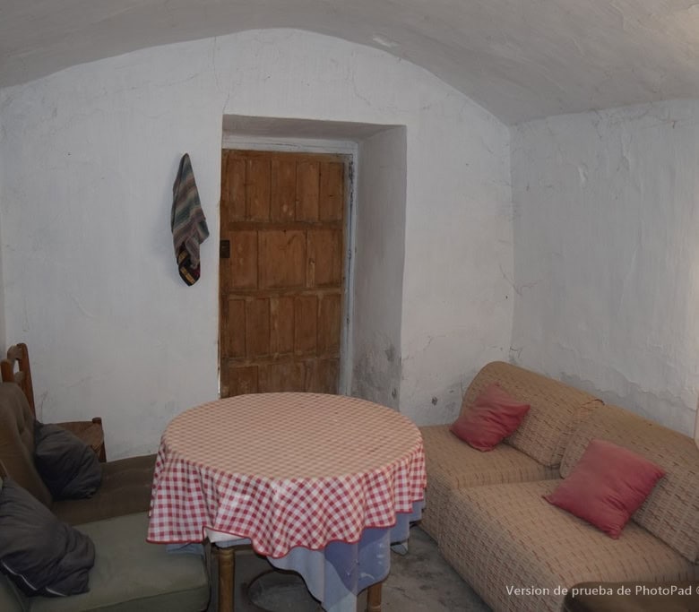 Charming cave house interior in Cullar, Granada, featuring rustic white walls and simple furnishings.