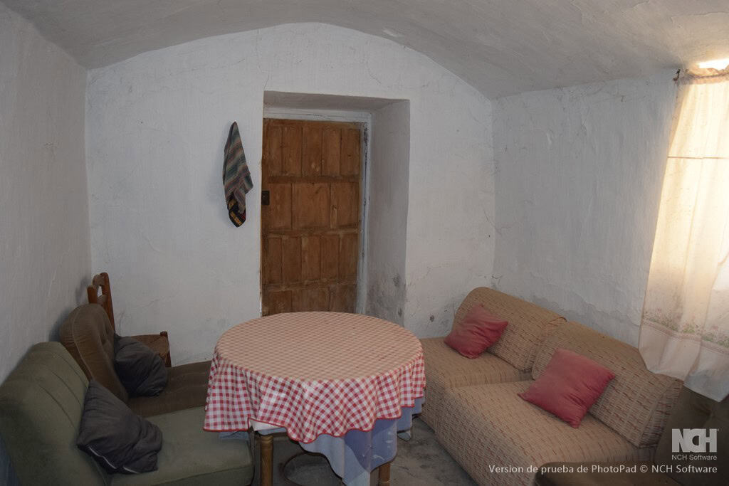Charming cave house interior in Cullar, Granada, featuring rustic white walls and simple furnishings.
